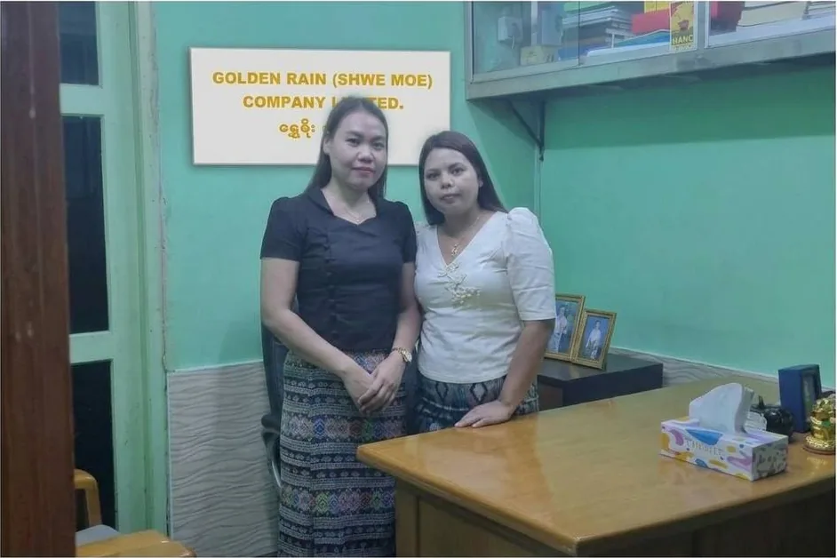 Two members of Golden Rain staff standing beneath the company nameplate